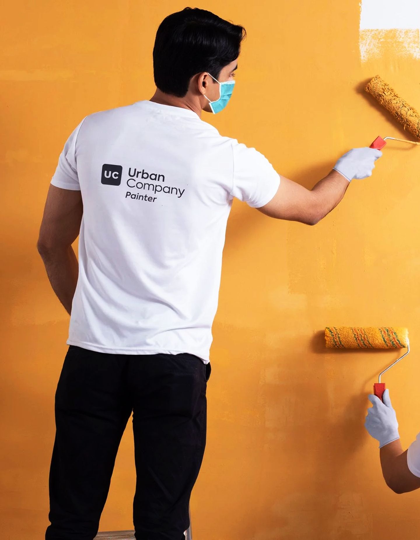 A two painters paint a wall orange for a job with Urban Company