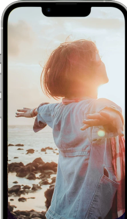 A visual representation of a mobile device with a beach background displaying an image of a woman feeling free and empowered as she raises her arms.