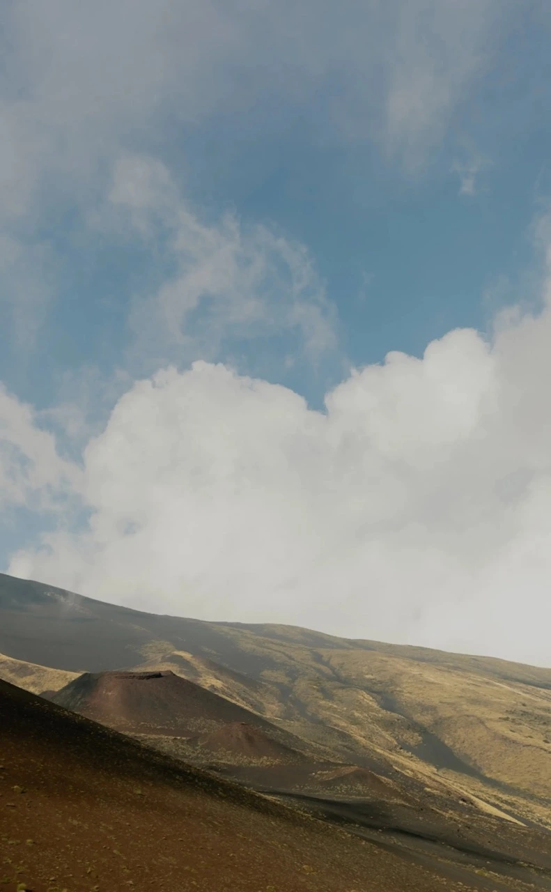 A photograph of a desert landscape, featuring mountains and a blue sky with clouds.