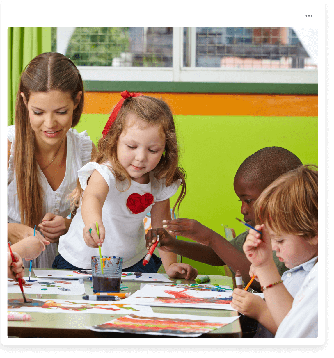 a group of children sitting around a table painting