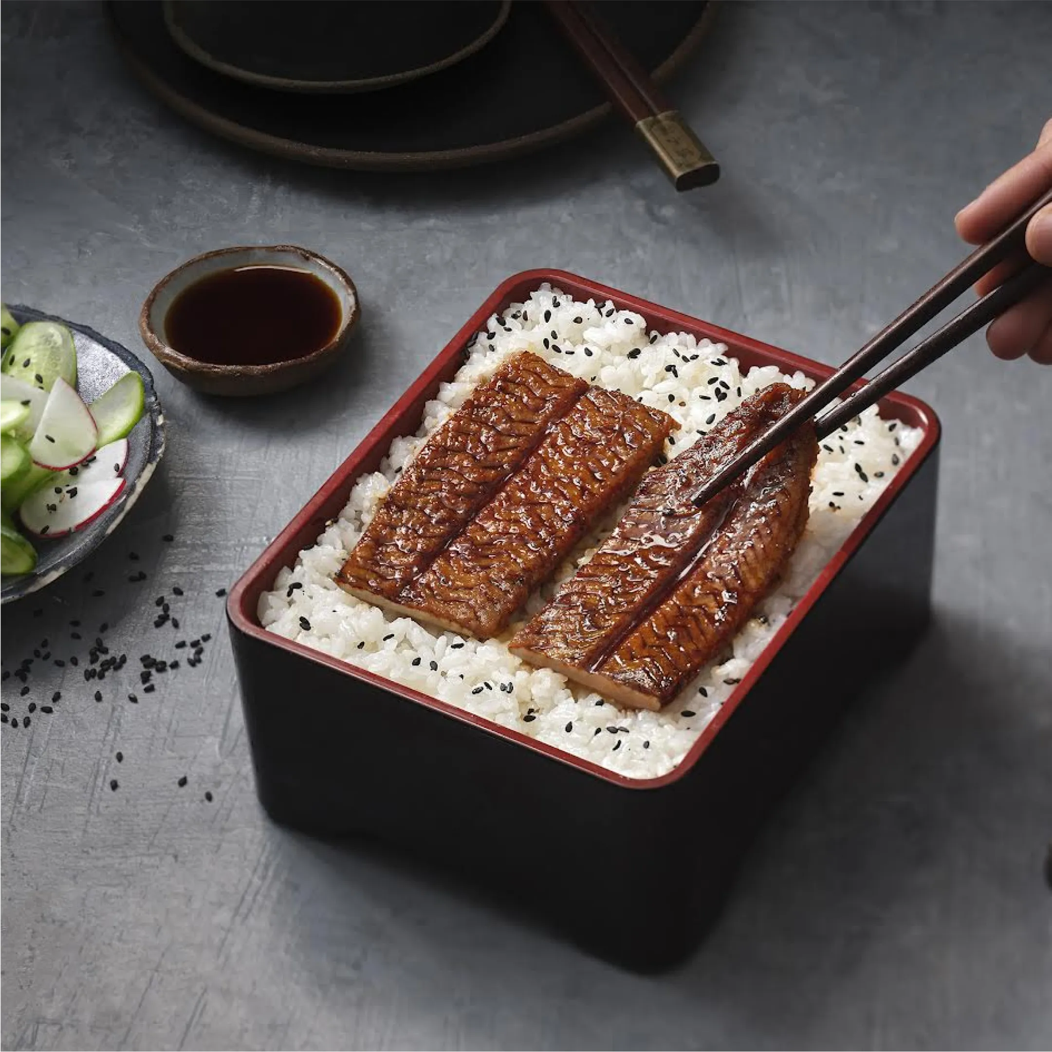 A person holding chopsticks over a bowl of rice.