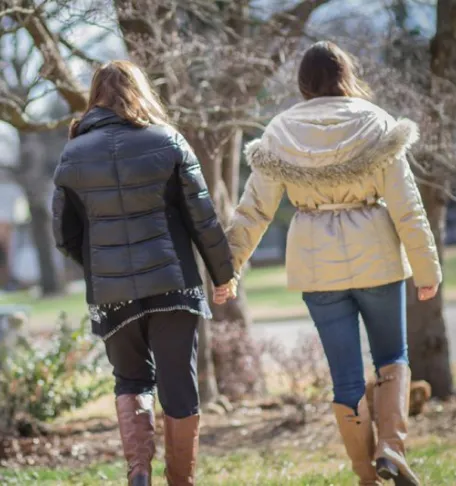 two women walking in a park holding hands