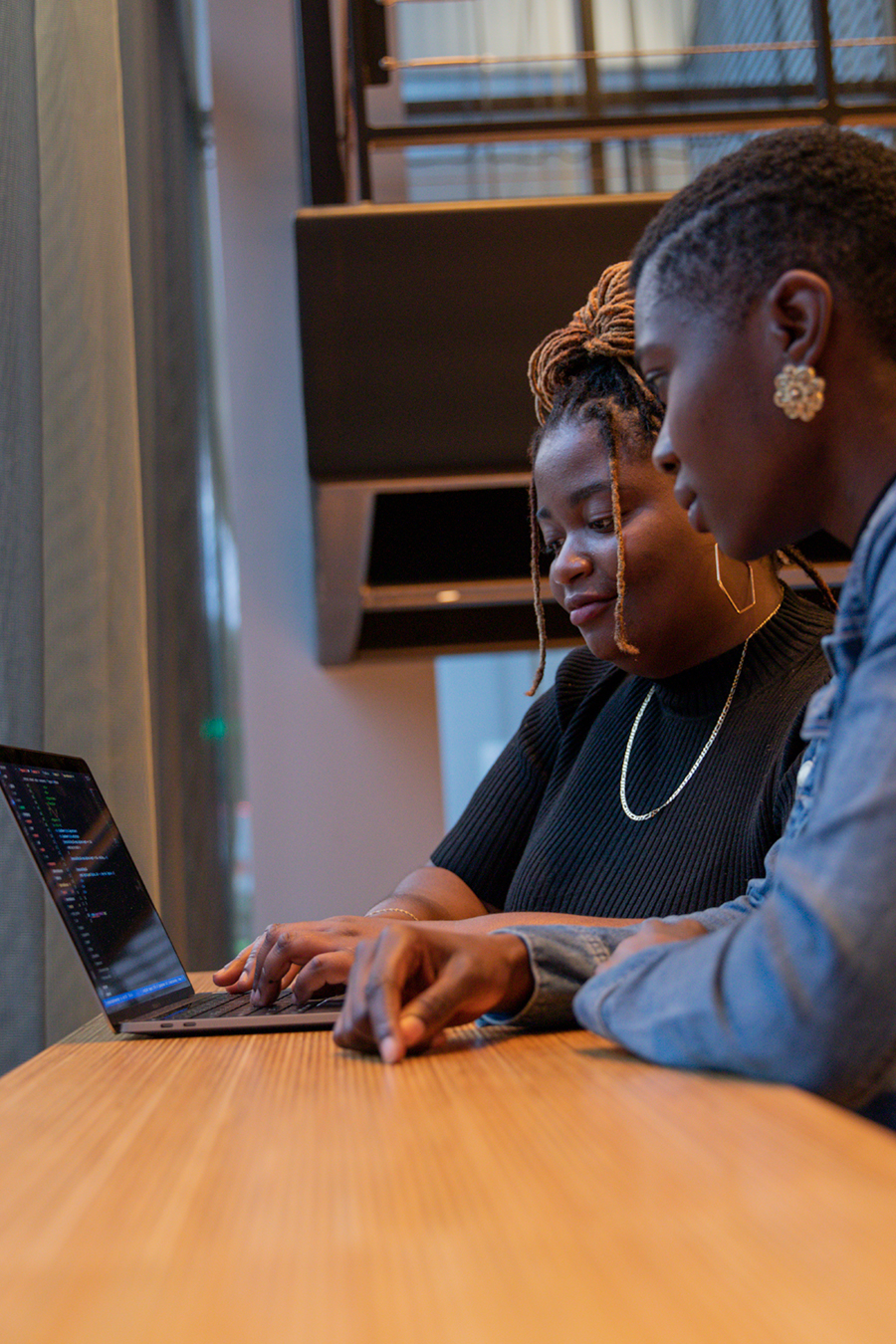 two rc alumni using laptop in front of window