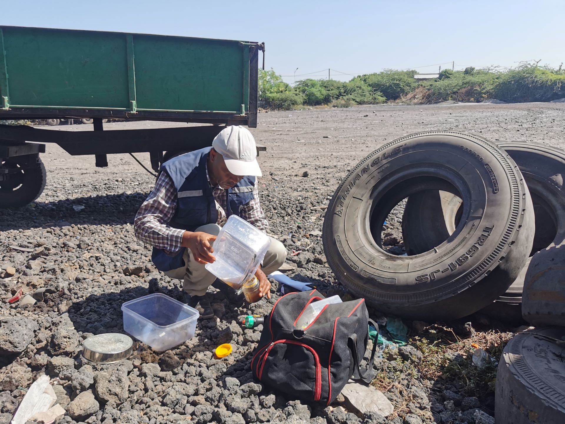 Man in a crouched position collecting mosquito larvae