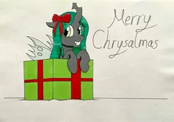 Size: 3500x2445 | Tagged: safe, artist:killerteddybear94, derpibooru import, queen chrysalis, changeling, changeling queen, pony, g4, bow, box, christmas, cute, cutealis, female, hair bow, holiday, image, jpeg, looking at you, pony in a box, present, pun, traditional art