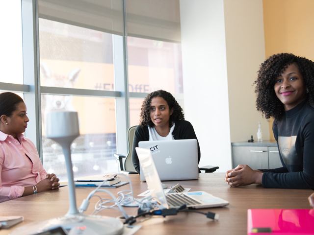 Three ladies sitting in a meeting room.