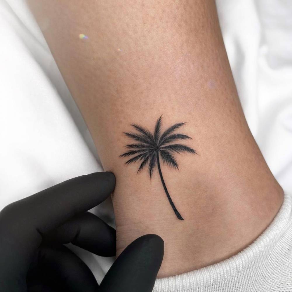 Fine line palm tree tattoo on the ankle.