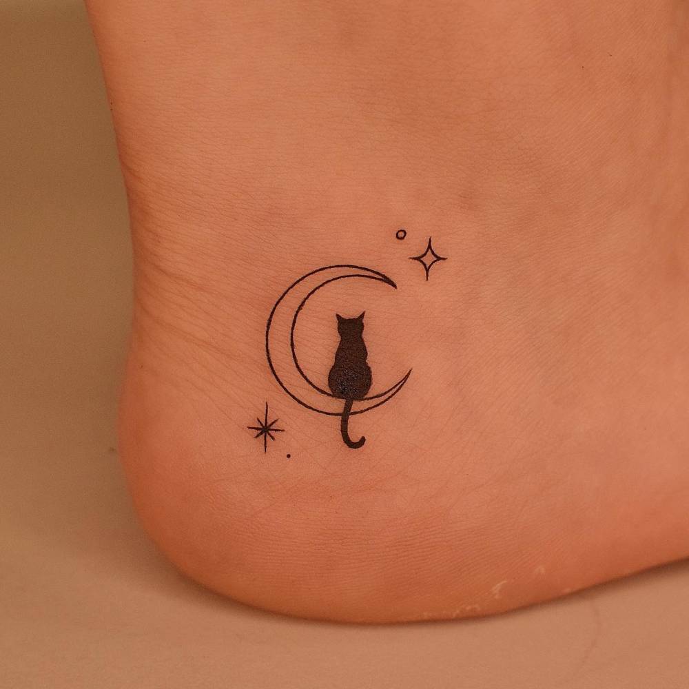 Crescent moon and black cat tattoo done on the ankle, minimalistic style.