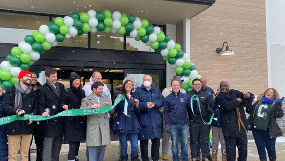 Kristin Mink, Marc Elrich and other County leaders holding cut green ribbon outside Sprouts Market Burtonsville.