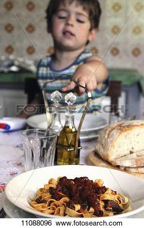 Stock Images of A little boy sitting at a table pointing to a.