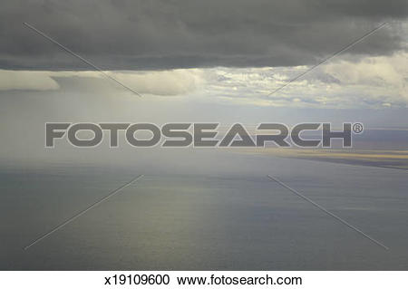 Stock Photography of Cumulus clouds and rain showers over sea.