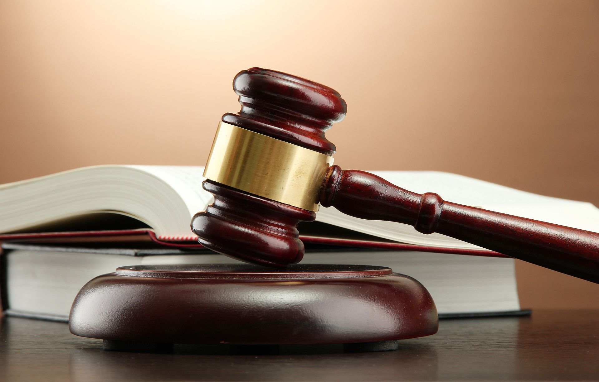 wooden gavel and books on wooden table,on brown background.