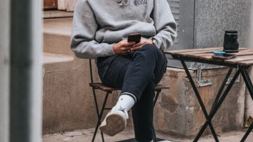 man in gray sweater sitting on brown wooden folding table