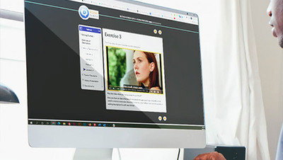 A person looking into a computer display which shows our Learning Modules on screen