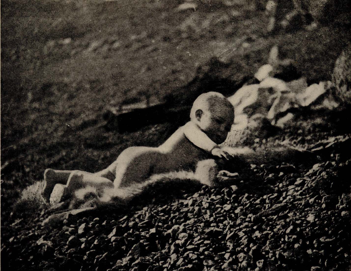 Baby lying on fur, playing with Pebbles.