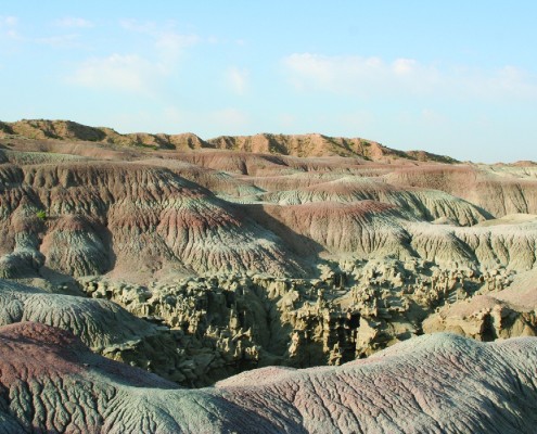 On top of the sandstone that forms Fantasy Canyon, a mudstone layer with alternating gray, olive, and reddish-purple stripes erodes into characteristic badland topography with guttered slopes.