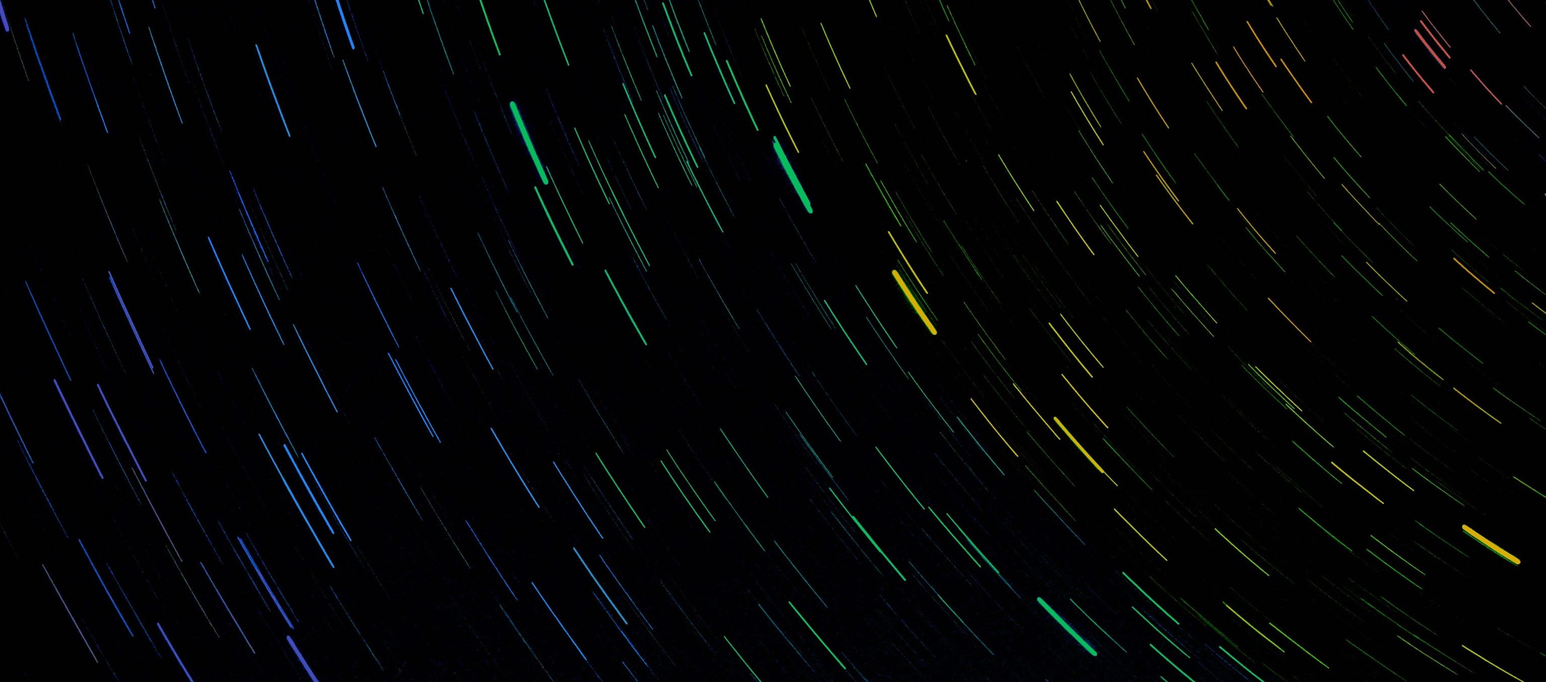 Photo of a trail of stars, which has been colourized to resemble a rainbow