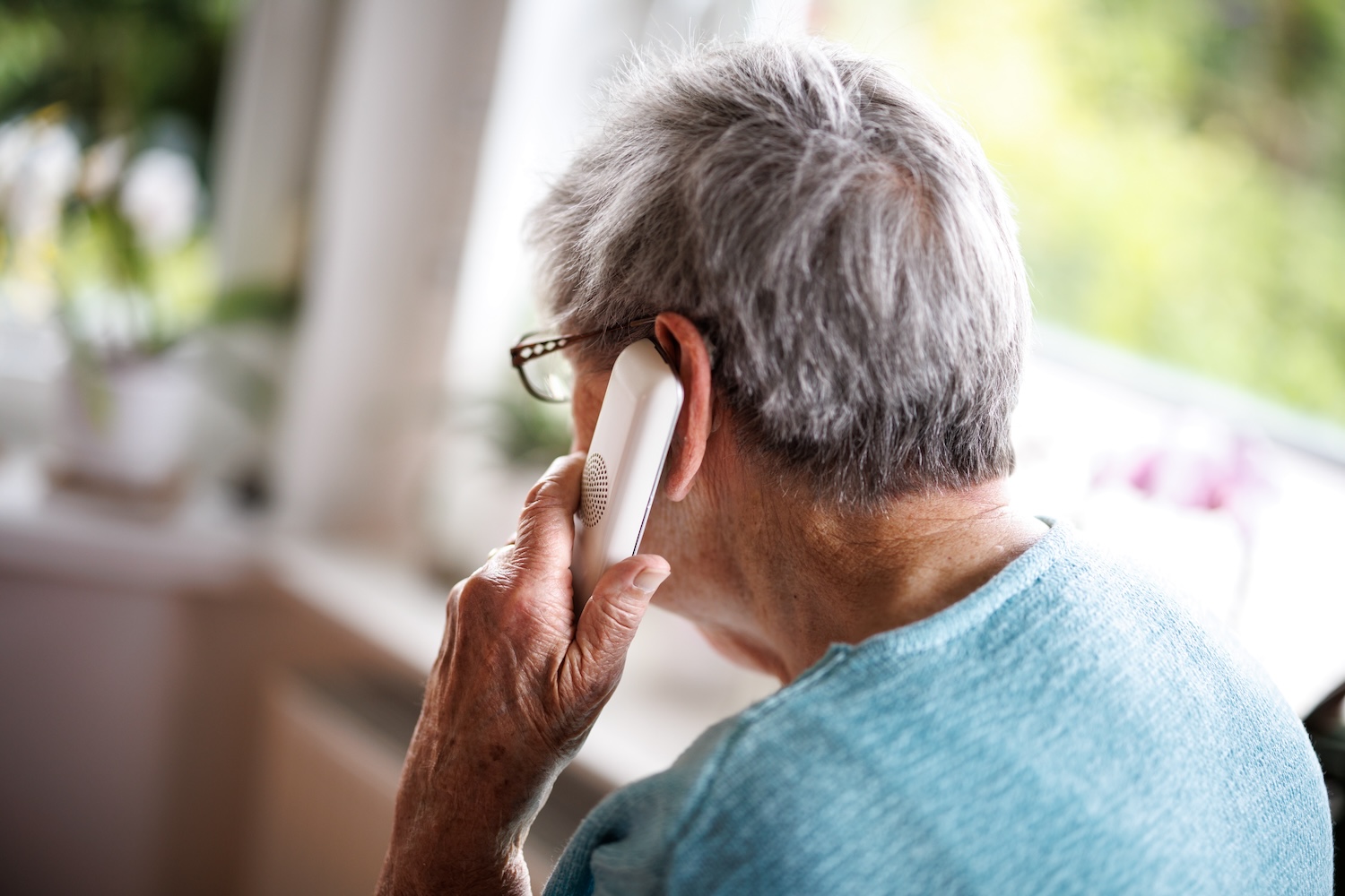 Elderly person talks on a phone.