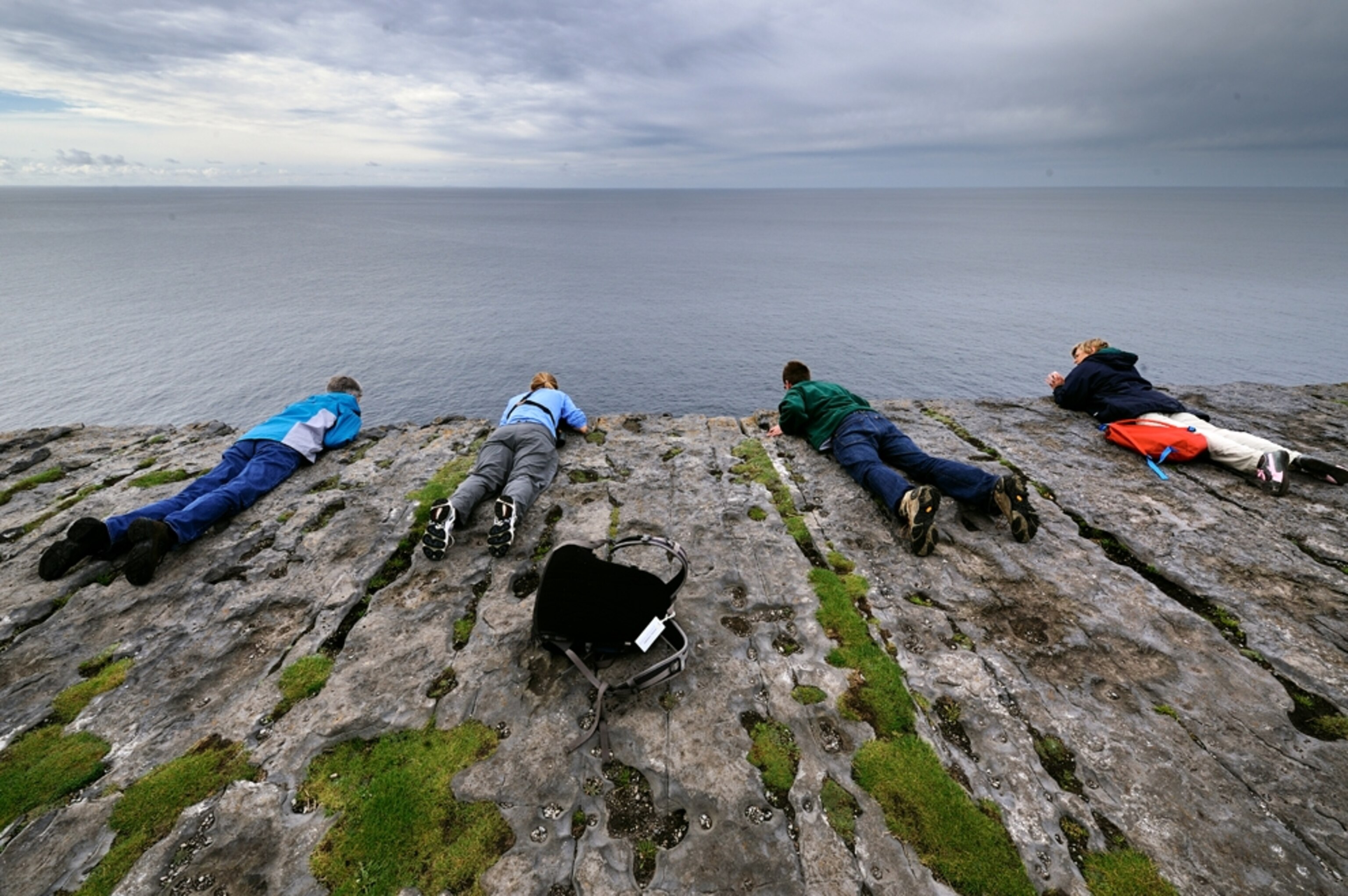 People lying down to look over cliff