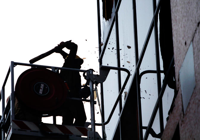 A firefighter smashes glass windows of the AMRI Hospital nursing home as he searches for survivors ? AP Photo