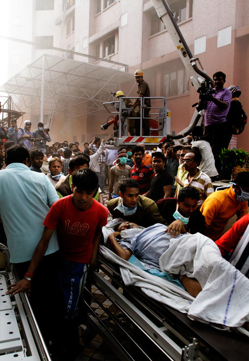 People help carry a patient out of a hospital after it caught fire in Kolkata, India, Friday, Dec. 9, 2011. The fire swept through the hospital early Friday, sending emergency workers scrambling to evacuate patients and medical staff from the smoke-filled building, officials said. ? AP Photo