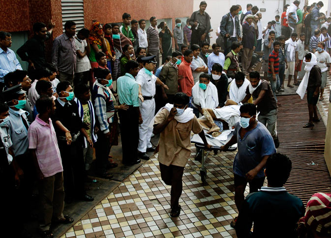 People help carry a patient out of a hospital after it caught fire in Kolkata, India, Friday, Dec. 9, 2011. The fire swept through the hospital early Friday, sending emergency workers scrambling to evacuate patients and medical staff from the smoke-filled building, officials said. - AP Photo