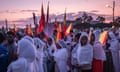 A group of women wearing white scarves and carrying flags