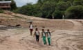 Four children walk along a dried up river in the Amazon