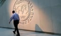 A man walks past the International Monetary Fund (IMF) logo at its headquarters in Washington