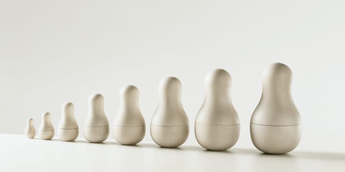 Eight minimalist matryoshka dolls sit next to each other in ascending order of size. The dolls are all white, with no other ornamentation on them.