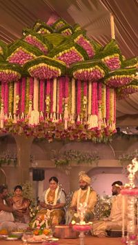 #wedding #mandap #indianweddings #southindianwedding #decor  Follow for More--- For Mithrita and Nikash’s wedding, we orchestrated a distinct setup at the hall’s center, deviating from the conventional. The 180-degree seating arrangement elicited awe from guests, while the mandap’s four intricately designed pillars stood as a testament to our craftsmanship. The focal point, however, was the trio of hanging structures adorned with exquisite floral crafts, captivating all who attended.