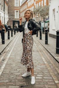 10+ Cool Ways To Style A Leopard Satin Skirt: @laurie_ferraro wearing a black leather jacket, a white t-shirt, a leopard skirt and white sneakers.