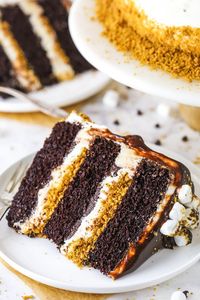 This S’mores Cake is an amazing combination of moist chocolate cake, toasted marshmallow buttercream, graham cracker crunchies and chocolate ganache! #smores #marshmallows #grahamcrackers #chocolate