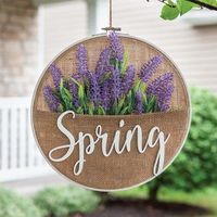 Spring Lavender Burlap Sampler Wall Hanger features lavender florals and the word, “Spring” in white cut-out lettering over a burlap background. Hanger comes with a jute string hanger for wall display and measures 11” high by 10.75” wide by .25” deep.