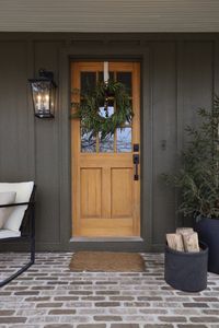 Porch before and after by Nadine Stay | DIY porch brick floor. DIY flagstone path. DIY custom porch railing. Beige porch railing paint color. A craftsman porch railing. Box trim on porch railing posts. Green exterior paint color - Muddled Basil by Sherwin Williams. How we added curb appeal to our porch. A charming porch renovation. How we incorporated flagstone, stone steps, and brick in our porch remodel. Christmas front door. #porch #porchmakeover #porchrailing #brickporchfloor #flagstonepath