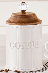 The Circa Coffee Canister serves a side of charm alongside your daily cup of joe. Finished in white, the ceramic jar features an embossed paneled design with beaded trim and bold "COFFEE." An airtight mango wood lid with a vintage-style glass and metal doorknob finial completes the look.