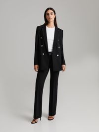 Tailored double-breasted blazer that features notch collar, silver buttons, open front pockets and finishes just below the hip. Lined except for the sleeves. Made of heavy stretch jersey.