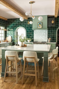 Designed by @rebeccagibbs.design, this fresh green kitchen feels timeless and trend-forward with sage cabinets and a glossy emerald tile backsplash. Our timeless Clemente Wall Lights by AERIN and Prescott Medium Mobile Chandelier by kate spade new  york add a beautiful touch of brass. Visit the link to see more colorful designs like this one. 📷: The Good Things