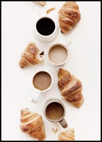 Photograph of a delicious table with coffee and croissants. This kitchen wall art is a great idea to add to your walls if you are a coffee and croissant lover. This art print has a grainy photo structure.