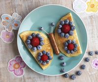 Plate with pancakes and berries in the shape of a butterfly