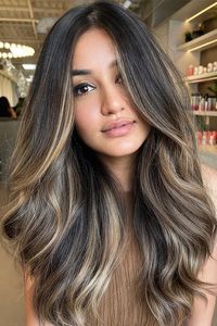 31. Cool-Toned Balayage This striking cool-toned balayage features a dark base with ashy, cool highlights that add depth and contrast. The voluminous waves enhance the dimension of the color, creating a dynamic and textured look.