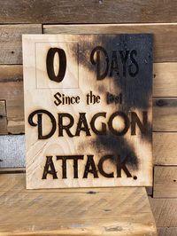 "It's only been zero days since last dragon attack! This wall sign would look perfect in any game room. Your companions should know that dragon attacks are a real thing to look out for... especially on game night! Burned edges and claw marks give it a little authentic feel. Your workplace sign will be 10x12\". Stay aware of workplace dangers! *each sign will be slightly different. Scratches and burn marks are random dragon markings."