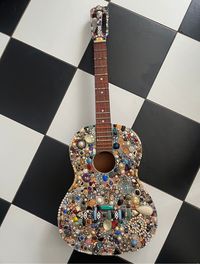 A true one of a kind conversation piece. The first one I did is hanging on my wall and no one comes into my house without admiring it. Do not be alarmed-this full size guitar was heading for the trash (not playable) when I took it in and introduced it to pounds of jewelry, rhinestones and beads-much of which also could've ended up in the landfill. So a bunch of unwanted stuff came together and now there is this beautiful one of a kind wall hanging-or display it on a guitar stand.   Ships for free but please allow 3 days for me to get it packaged properly, insured and shipped. may ship UPS or FedX -tracking will be provided.