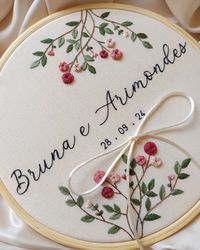 Porta-alianças feito com todo carinho para o grande dia de Bruna e Arimondes. Cada detalhe foi bordado à mão, refletindo a delicadeza e o amor desse momento tão especial. Que a união de vocês floresça assim como essas rosas! 🌹 O bordado foi produzido em tecido algodão cru 100% natural e emoldurado em bastidor de madeira, lixado e envernizado, medindo 22 cm. Para encomendar o seu, clique no link da bio! 💌