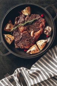 A pan seared and butter basted ribeye steak on a heavy cast iron skillet full of aromatics.