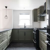 Deep green cabinets and island, dark counter tops, black hardware and fixtures