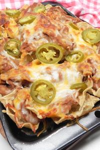 Easy Nachos with Refried Beans | "You can't go wrong with beans cheese and jalapenos. I've been making these since I was a kid and I never get tired of them." #footballrecipes #gamedayrecipes #tailgatingrecipes #superbowlrecipes #superbowlparty #superbowlpartyideas