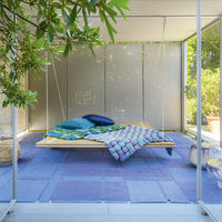 From Paola Lenti's Eres collection, the Shibui, designed by Francesco Rota, appears as a relaxing, suspended platform made of bamboo sticks and jute straps. Paired with a mattress, it invites comfort and integrates seamlessly into the environment, crafting a peaceful retreat suspended in both space and time.