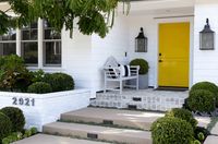 white home exterior with bright yellow door, pantone buttercup used on front door, lemon yellow