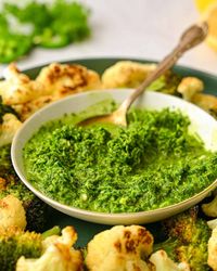 Green harissa in a bowl with a spoon in it.